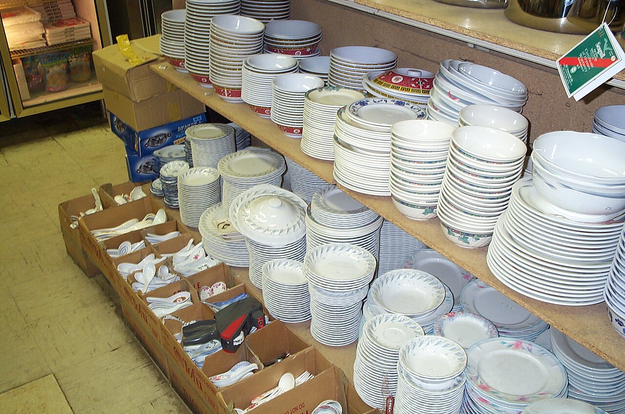 Stacks of white porcelain bowls and plates on shop shelves
