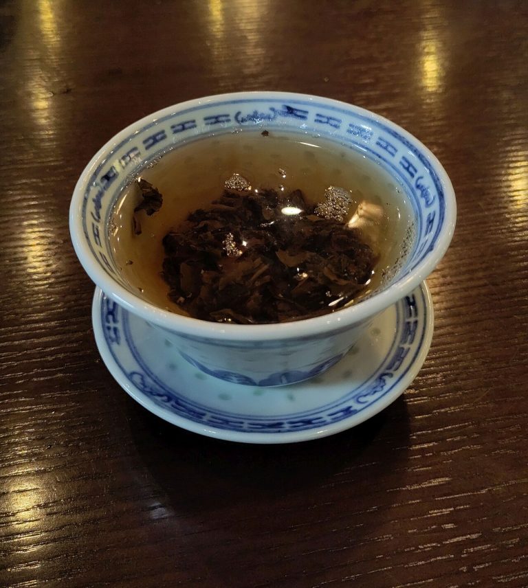 Tea leaves brewing in a blue-and-white gaiwan